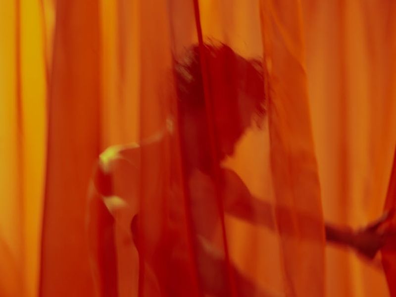 Person performing a dynamic movement in a minimalist room.